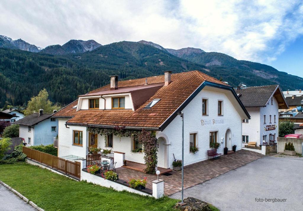 ein großes weißes Haus mit Bergen im Hintergrund in der Unterkunft Haus Arnold - Privatzimmer und Ferienwohnungen in Sillian