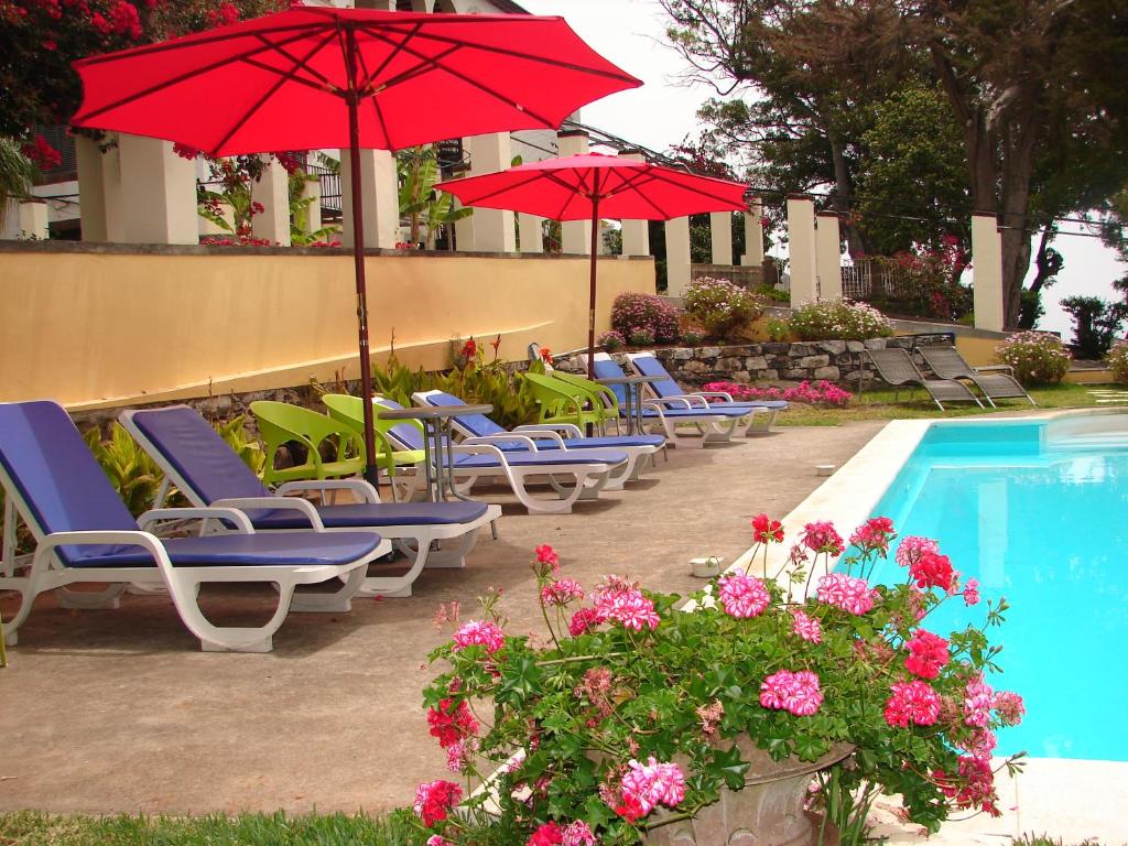 a group of chairs and umbrellas next to a pool at Purple Studio in Funchal