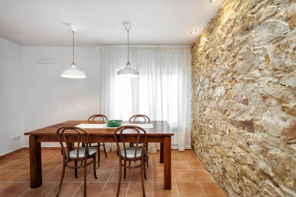 a dining room with a stone wall and a table and chairs at Can Terrats in Blanes
