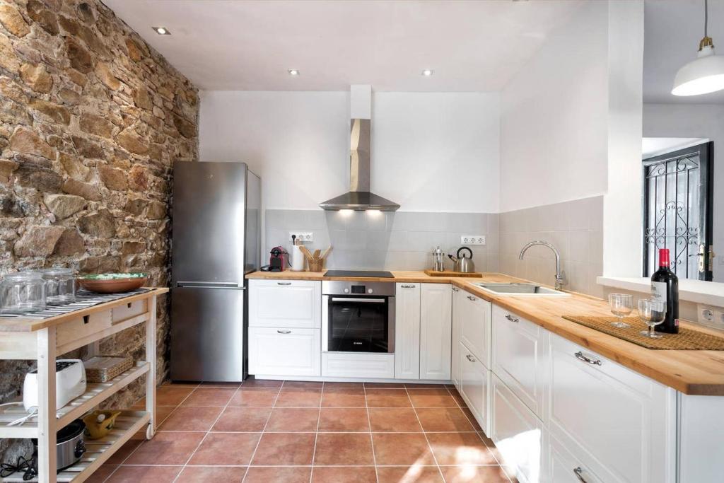 a kitchen with white cabinets and a stone wall at Can Terrats in Blanes