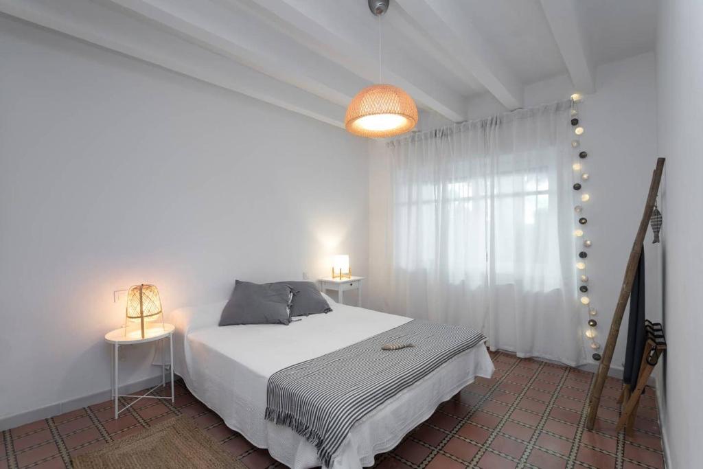 a white bedroom with a bed and a window at Can Terrats in Blanes