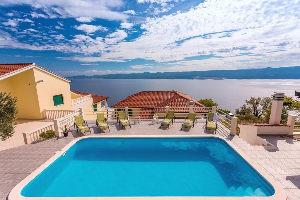 a swimming pool with chairs and a view of the water at VILLA MASLINA, with private 32m2Pool, panoramic views on 100km coastline, 12 pax in Lokva Rogoznica