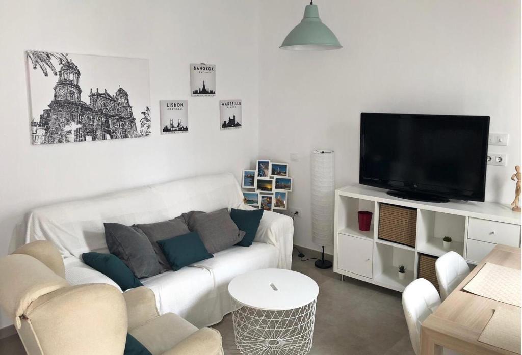 sala de estar con sofá blanco y TV en Apartamento Gran Teatro Falla-La Caleta, en Cádiz