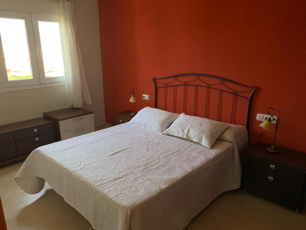 ein Schlafzimmer mit einem großen weißen Bett mit orangefarbenen Wänden in der Unterkunft Apartamentos San Miguel 2 in Almerimar