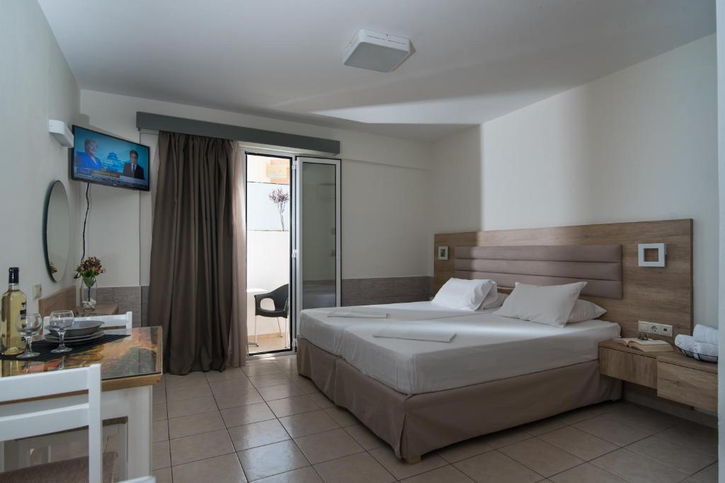 a bedroom with a bed and a desk and a mirror at Vagelis Apartments Malia in Malia