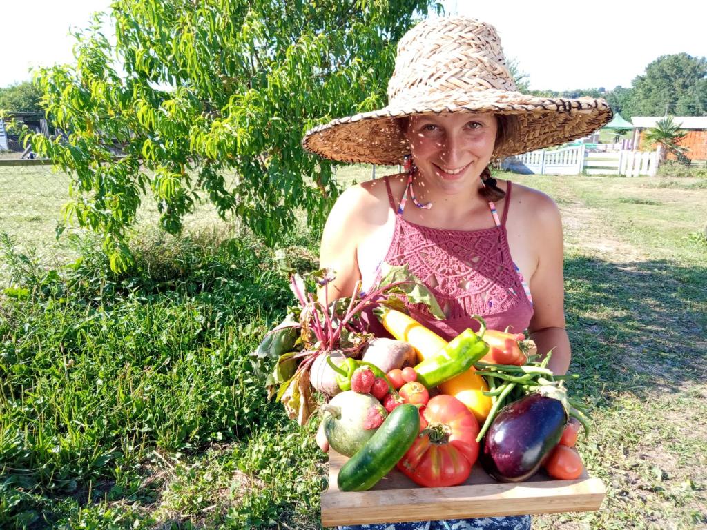 une femme dans un chapeau tenant un plateau de légumes dans l'établissement La petite ferme de Pouillon - Parc animalier - aire de loisirs, à Pouillon