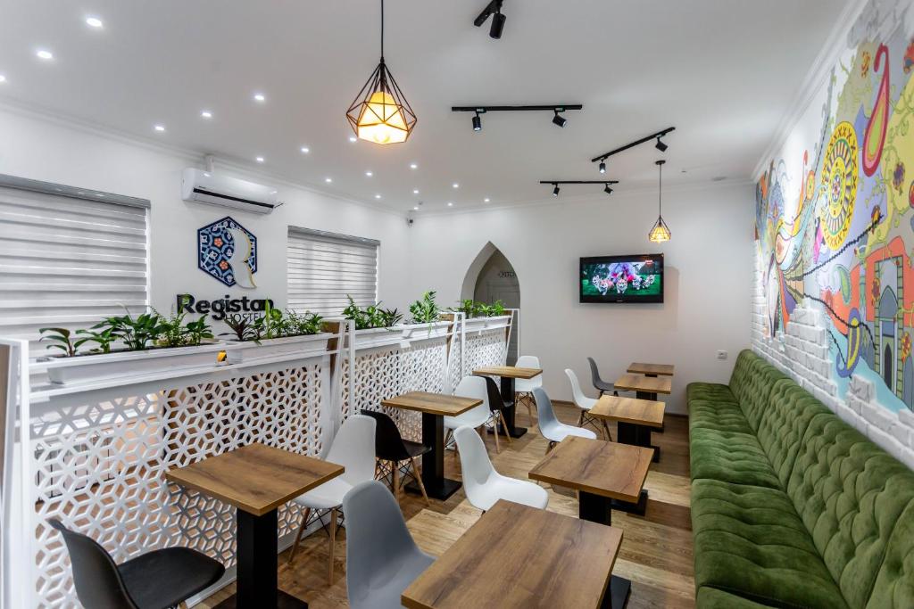 un restaurant avec des tables, des chaises et un canapé vert dans l'établissement Registan Hostel, à Samarcande