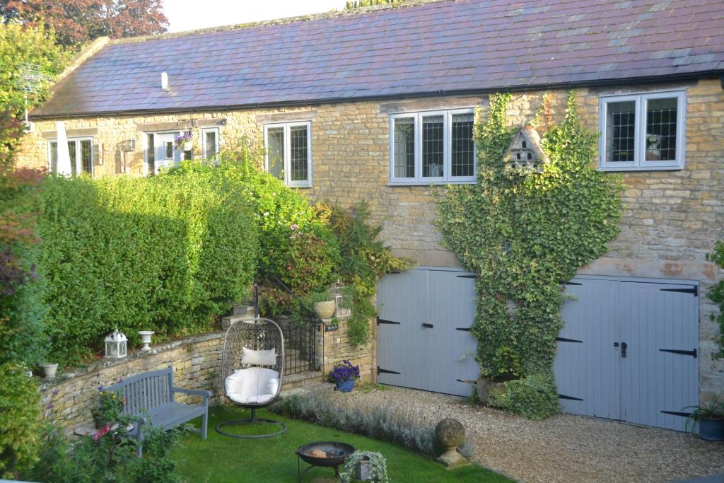 una casa de ladrillo con dos puertas blancas de garaje en Church Cottage Barn en Longborough