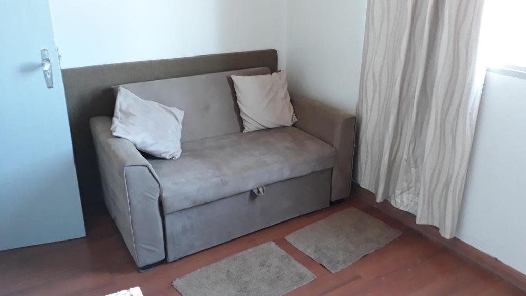 a couch with two pillows on it in a room at Edifício Belio in Cascavel