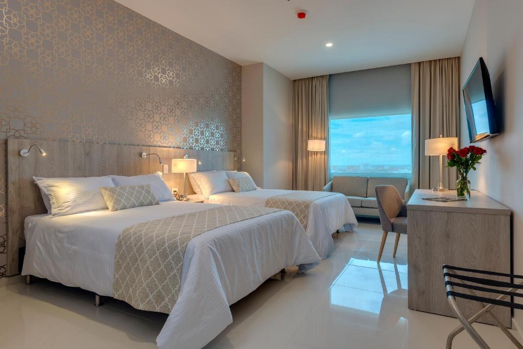 a hotel room with two beds and a television at Hotel Dorado Plaza Alto Prado in Barranquilla