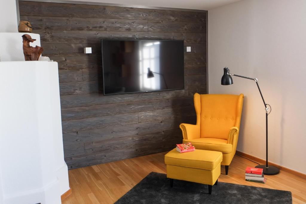 a living room with a chair and a television on a wall at Feriendomizil "Alte Post" II in Pronsfeld