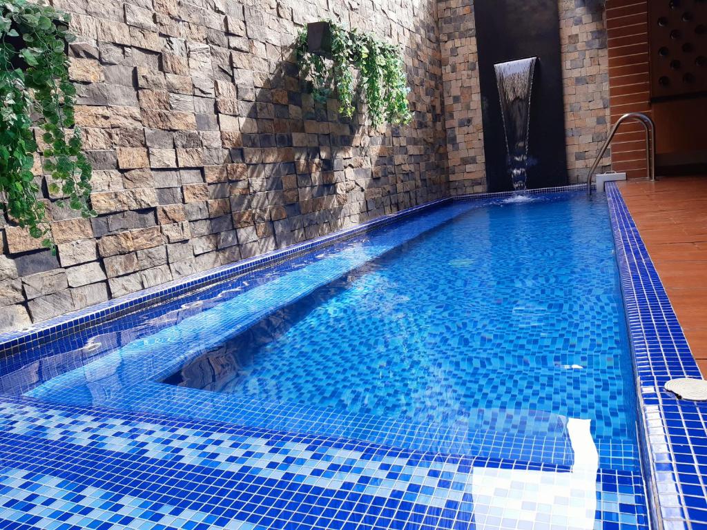 布卡拉曼加的住宿－Hotel León Dorado，一座拥有蓝色瓷砖和石墙的游泳池