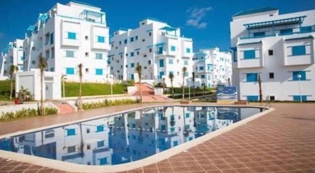 - une piscine en face de certains bâtiments blancs dans l'établissement luxy Appartement, Smir Park, M’diq ,TETOUAN, à Marina Smir