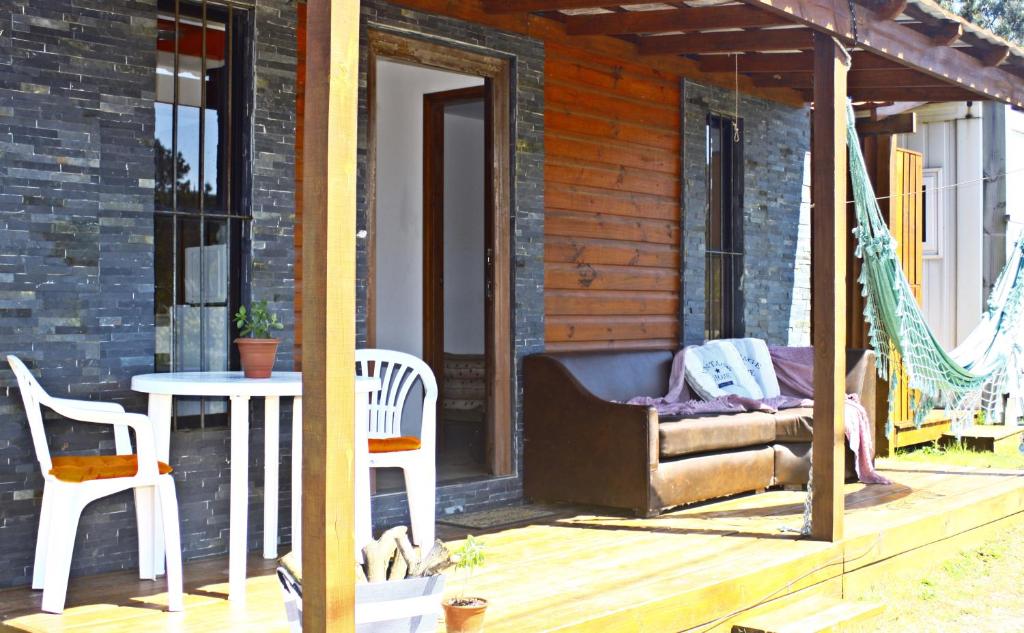 a porch of a house with a hammock and a table at Brisas Mágicas in Punta Del Diablo