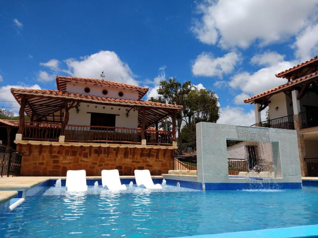 a villa with a swimming pool in front of a house at Hotel Campestre Ataraxia Barichara in Barichara