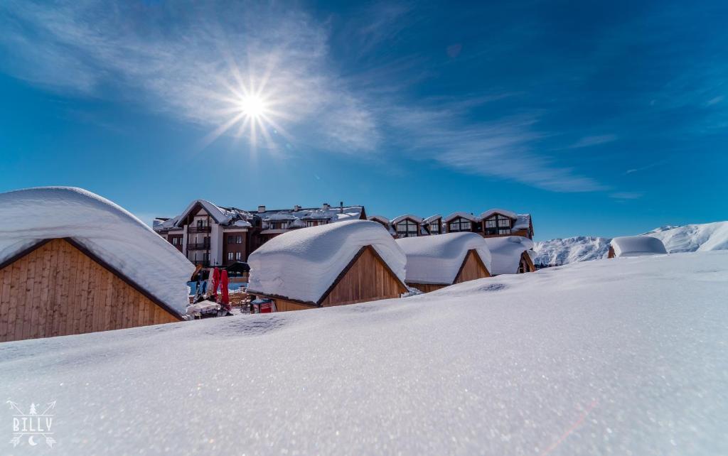 eine Gruppe schneebedeckter Gebäude mit der Sonne am Himmel in der Unterkunft New Gudauri M&N in Gudauri