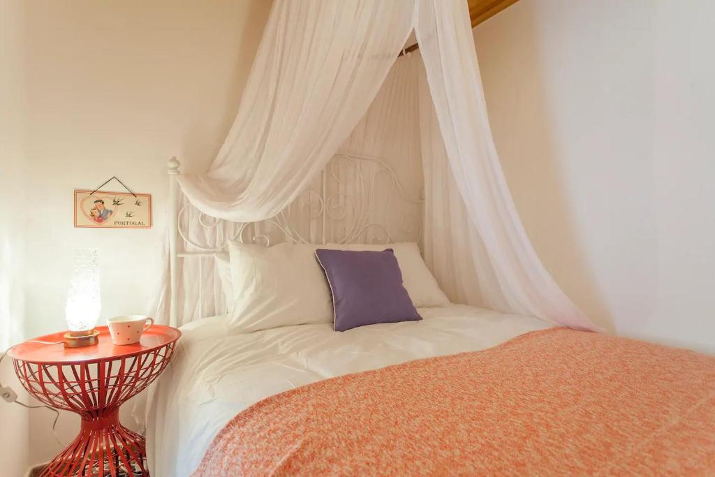a bedroom with a bed with a canopy and a table at Alfama Charming Apartment, By TimeCooler in Lisbon