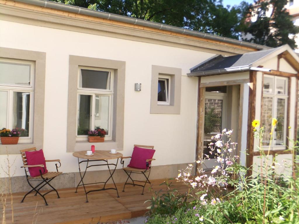 une terrasse avec des chaises et une table en face d'une maison dans l'établissement Gartenhaus Auguste, à Dresde