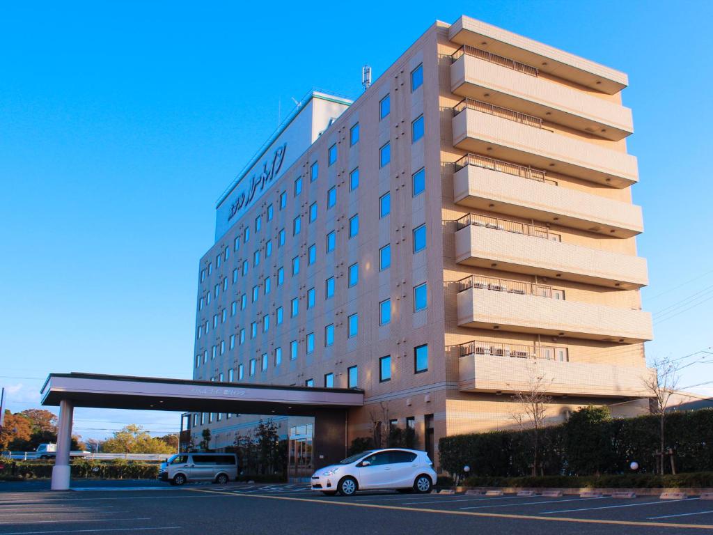 un edificio con due auto parcheggiate di fronte di Hotel Route-Inn Toyokawa Inter a Toyokawa