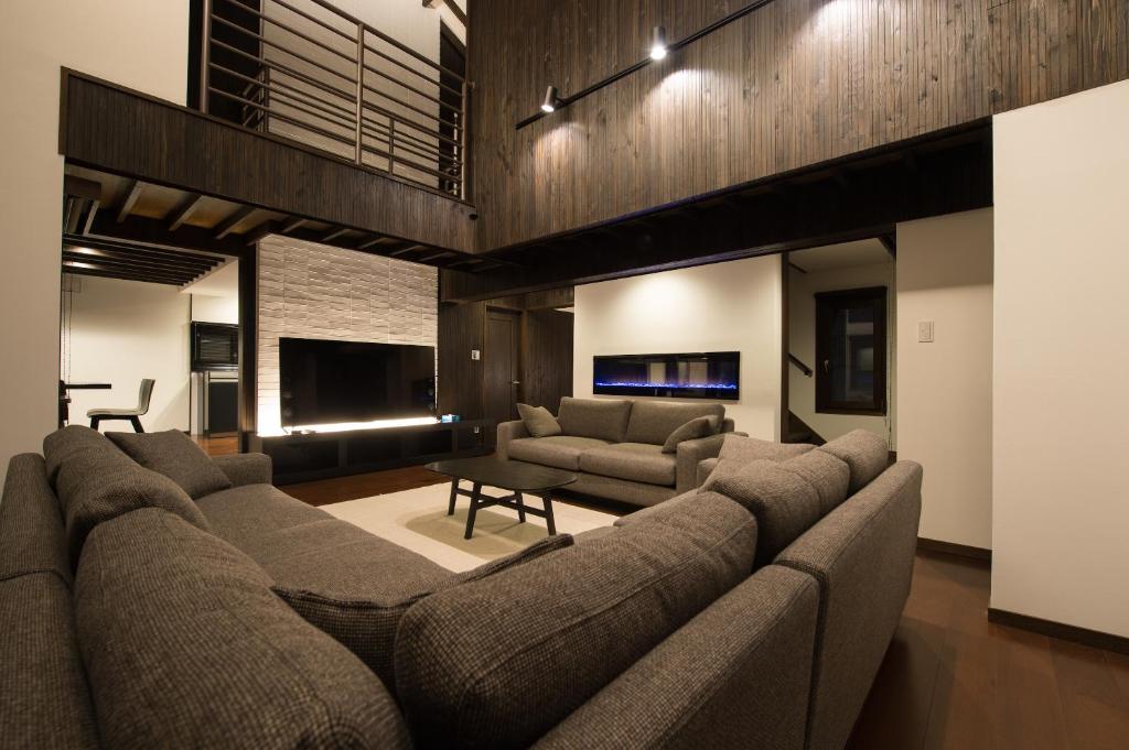 a living room with a large couch and a tv at La Plagne in Kutchan