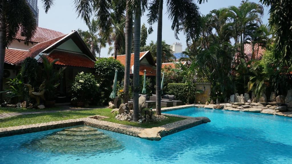 a swimming pool in a yard with palm trees at LePrive Resort in Pattaya South