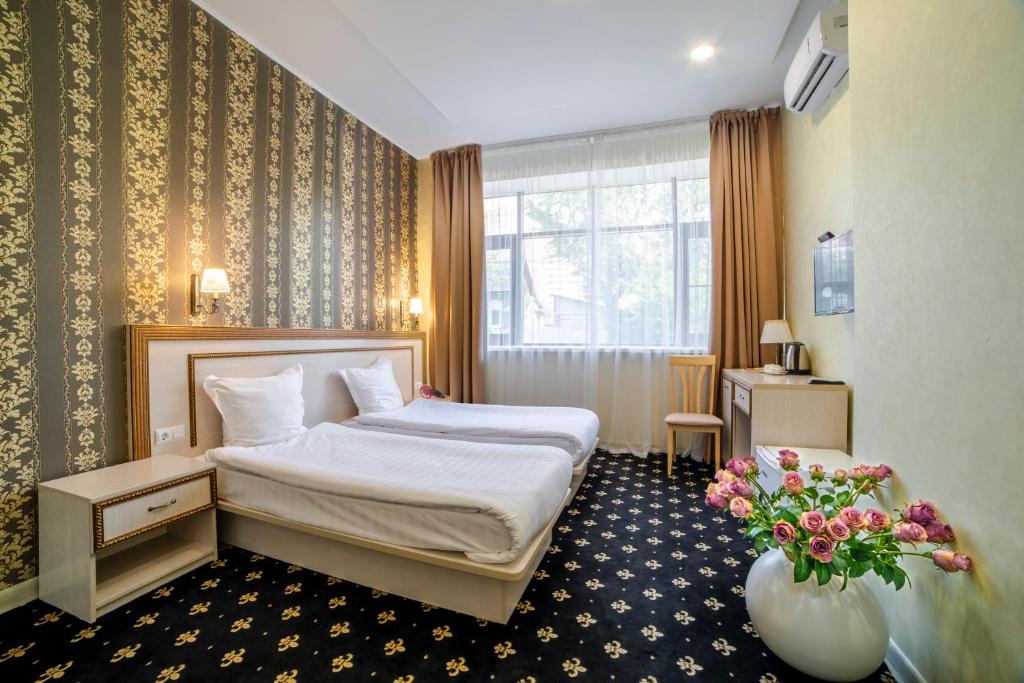 una habitación de hotel con una cama y un jarrón de flores en Hotel Ochagof en Irkutsk