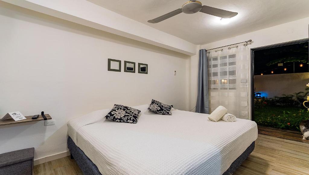 Vacation Rental - Standard Room at Casa Cocoa في كوزوميل: غرفة نوم بسرير ومخدتين ونافذة