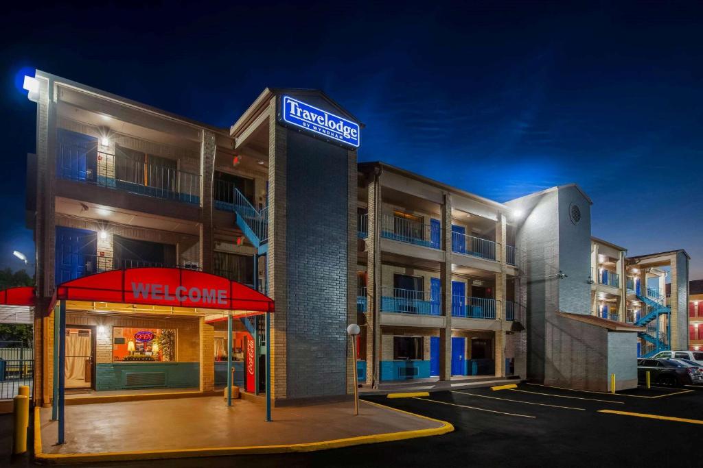 a hotel with a welcome sign in a parking lot at Travelodge by Wyndham Houston Hobby Airport in Houston