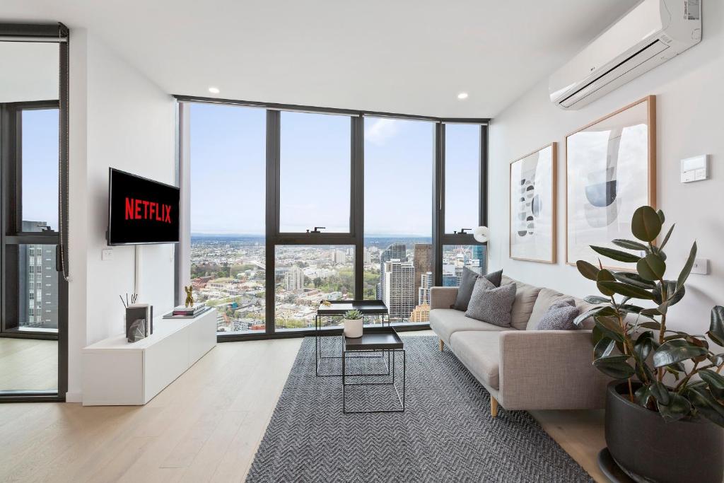 a living room with a couch and large windows at Luxuria Apartments - Avant in Melbourne