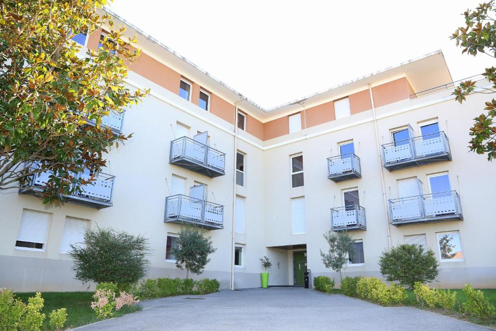 un edificio de apartamentos con balcones y entrada en Résidence Les Académies Aixoise, en Aix-en-Provence