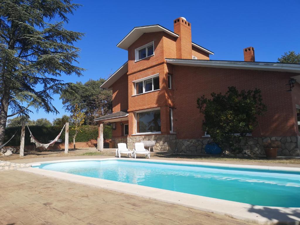 une maison avec une piscine en face d'une maison dans l'établissement Madrid Green, à Villaviciosa de Odón