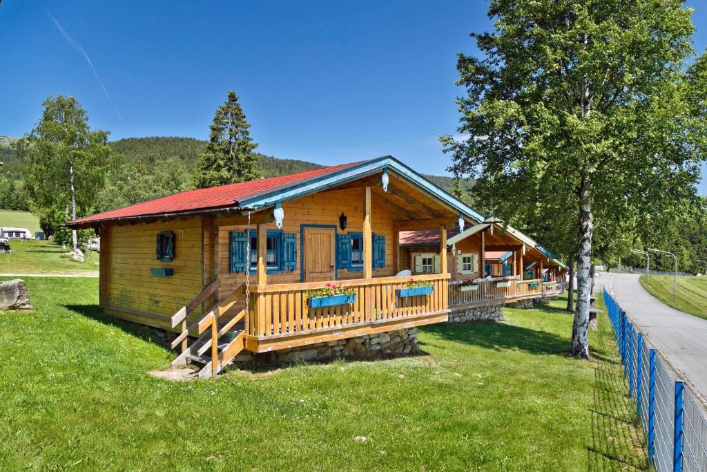 uma grande cabina de madeira com um telhado vermelho em Knaus Campingpark Lackenhäuser em Neureichenau