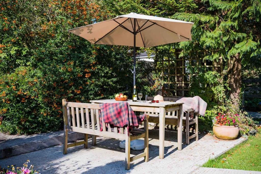 a table with an umbrella and a table and chairs at The Forge at Trevadlock Manor in Lewannick