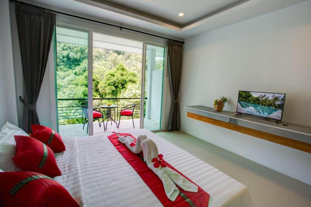 a bedroom with a bed with red pillows and a window at Kamala Amanah Hill in Kamala Beach