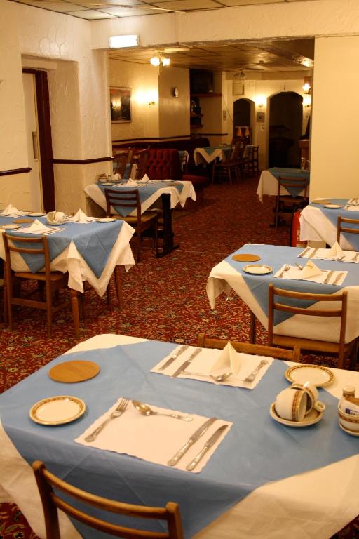 a dining room with blue tables and chairs with napkins at The Belvedere in Blackpool