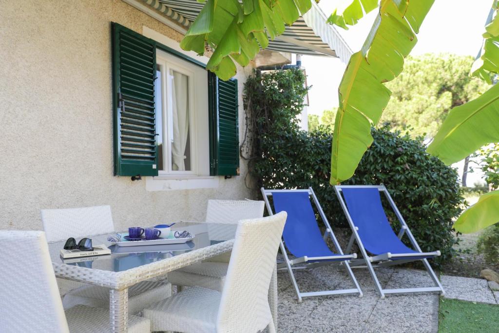a patio with chairs and a table and a window at Appartamenti Biodola Mare by HelloElba in Portoferraio