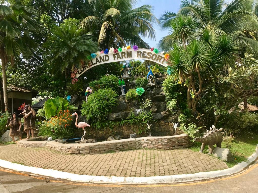 una cascada falsa en un parque con flamencos y palmeras en Loreland Farm Resort, en Antipolo