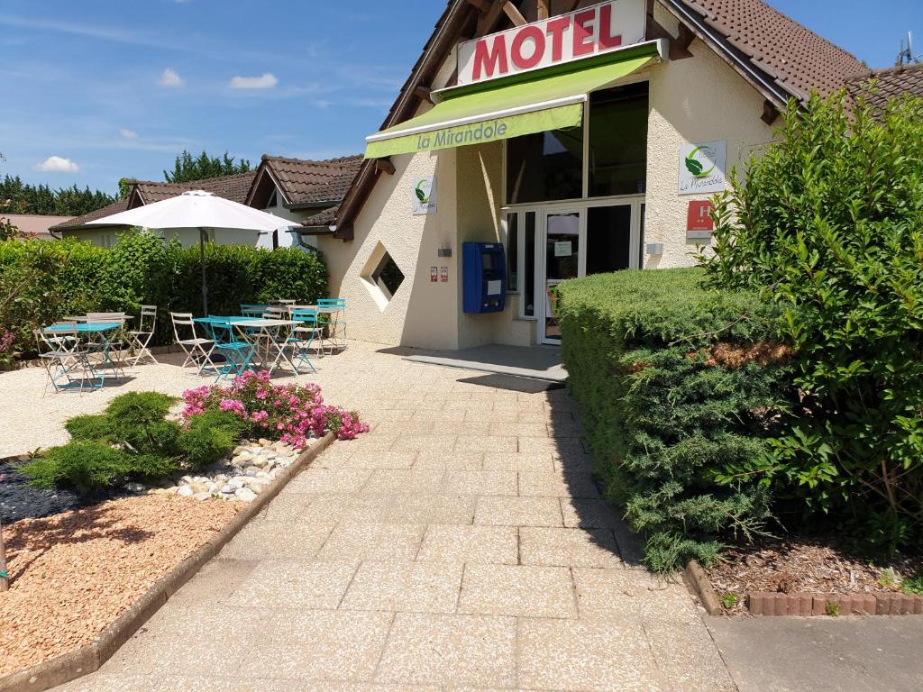 un motel avec des tables et des chaises à l'extérieur dans l'établissement Hôtel La Mirandole, à Tournus