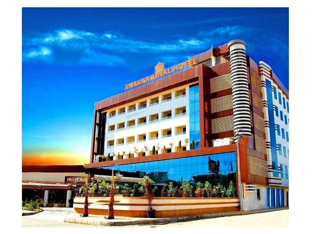 a hotel building with a sunset in the background at Ankawa Royal Hotel & Spa in Erbil