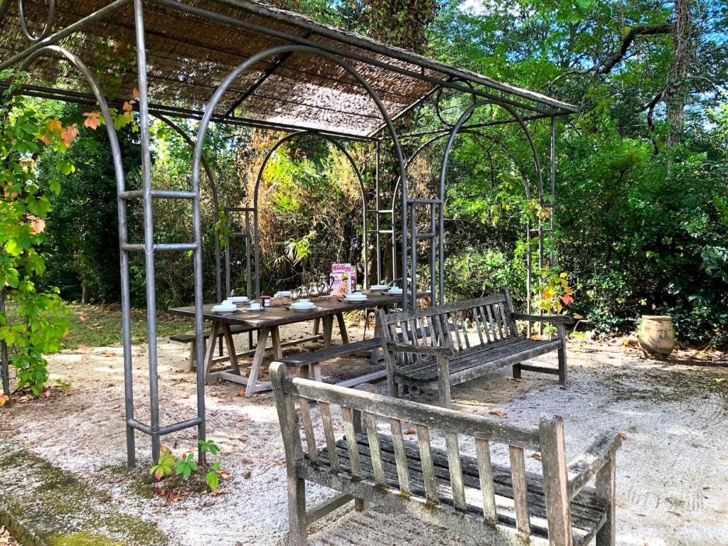 a picnic table and two benches under a pergola at Le Mas de Patrice in Quissac