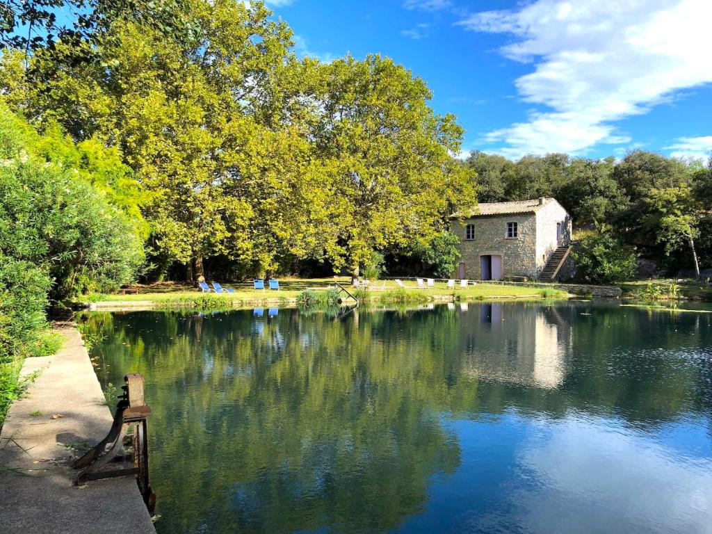 a lake with a bench in front of a building at Le Mas de Patrice in Quissac