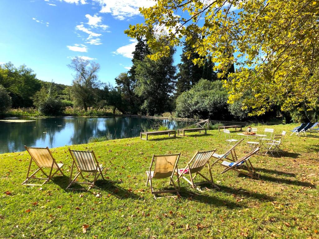 a group of chairs sitting in the grass next to a lake at Le Mas de Patrice in Quissac
