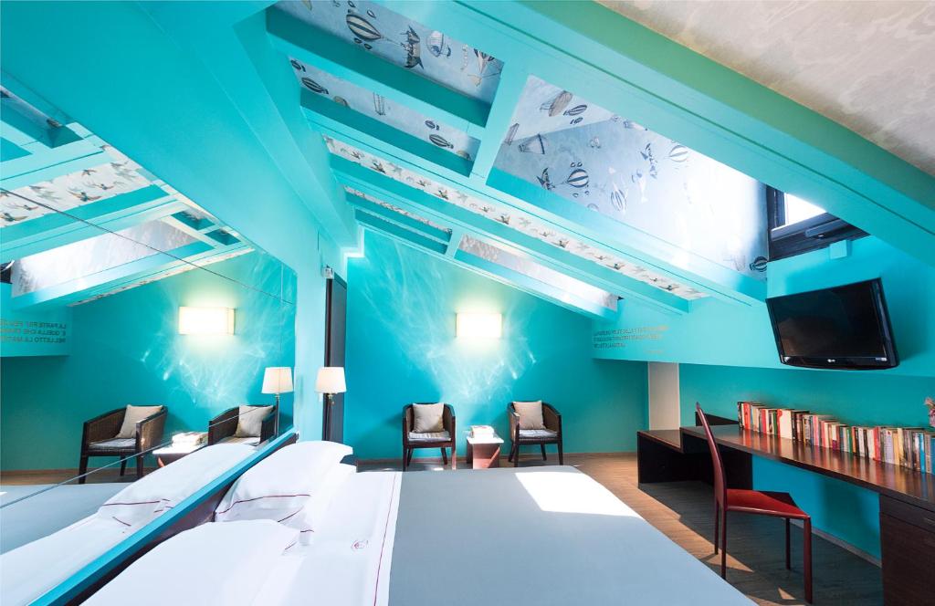 Phi Hotel Bologna في بولونيا: غرفة بجدران زرقاء وكراسي وتلفزيون