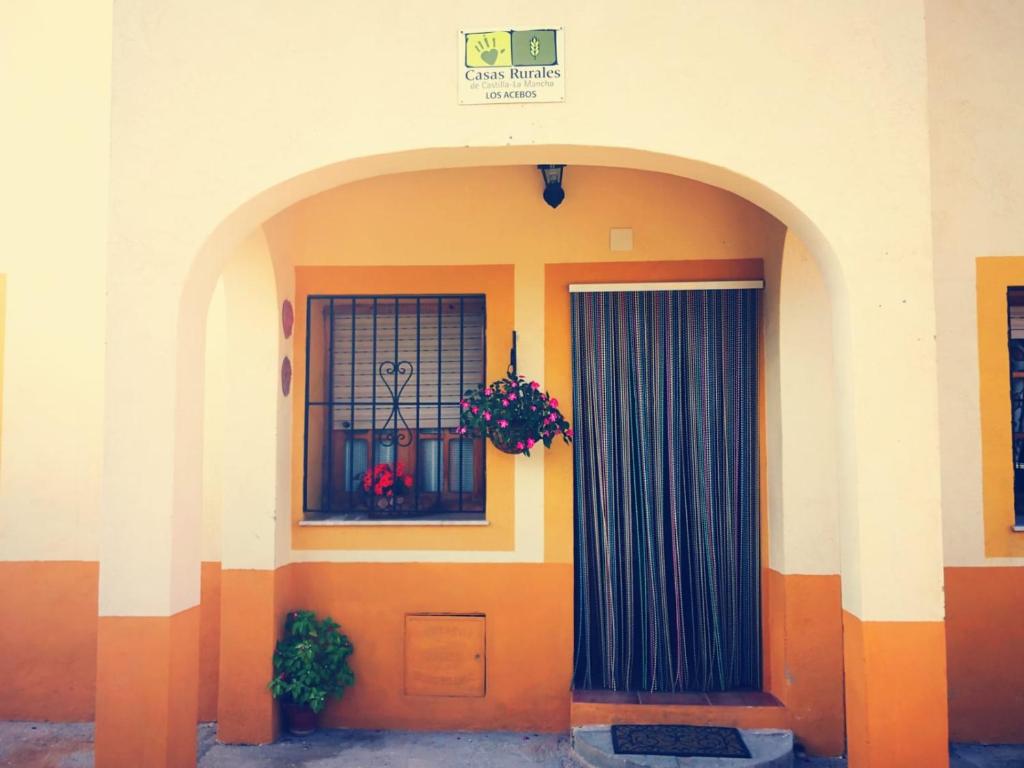 Casa Rural Los Acebos في ريوبار: مبنى فيه باب ونافذة فيها ورد