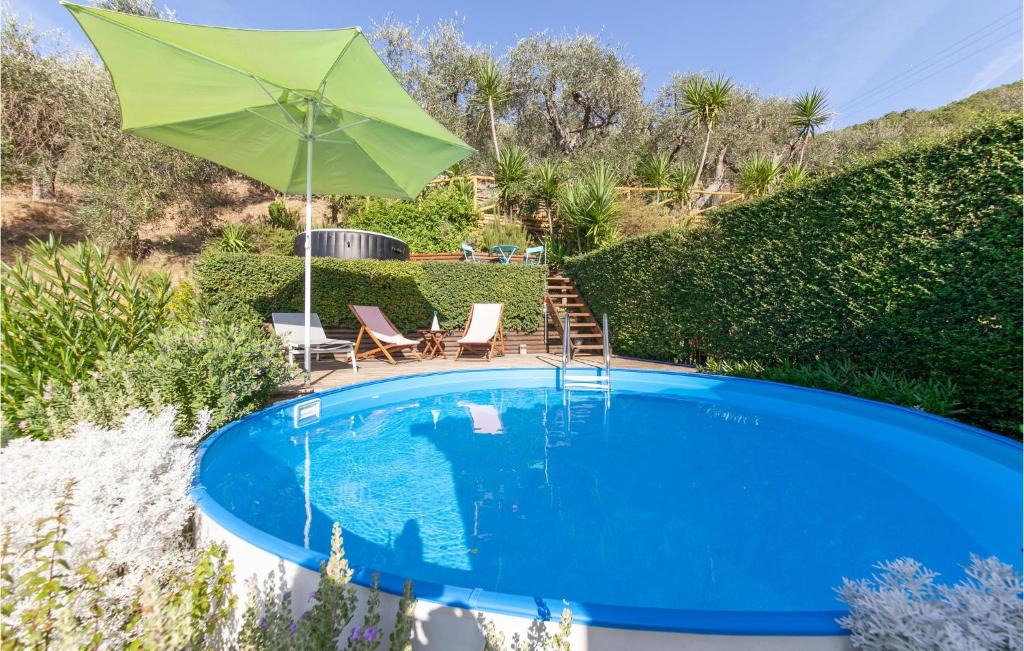 a swimming pool with a green umbrella and two chairs and a table at Nice Home In S,giuliano Terme Pi With Wifi in Asciano Pisano