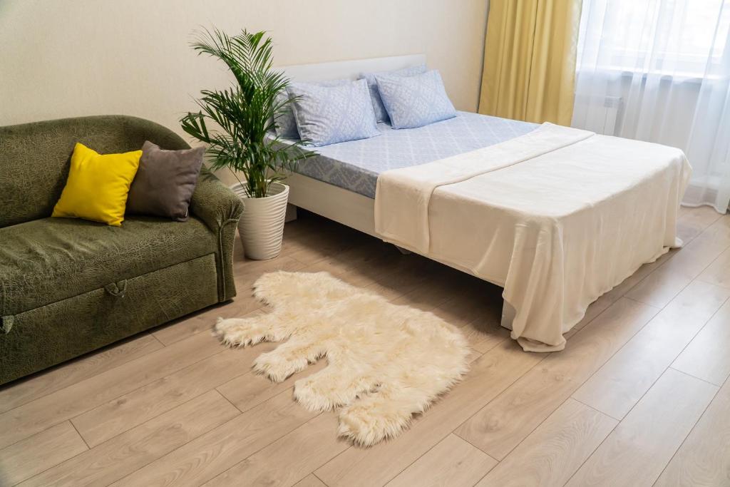 a bedroom with a bed and a couch and a rug at Апартаменты Красная, 10Б in Kemerovo