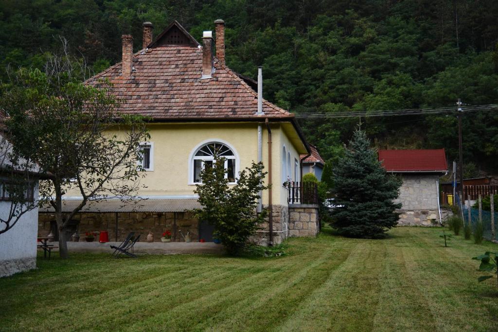 a house with a grass yard in front of it at Halháza Erdészlak Apartman in Sirok