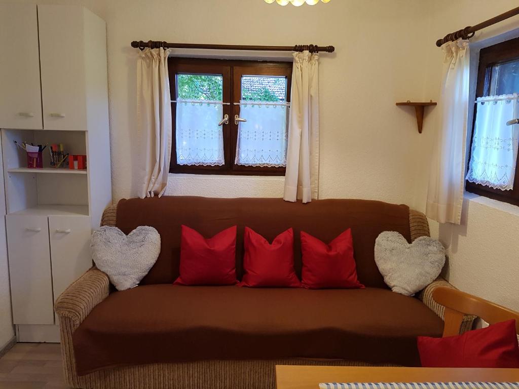 una sala de estar con un sofá marrón con almohadas rojas en Ferienwohnung Kraihof, 83703 Gmund am Tegernsee, en Gmund am Tegernsee