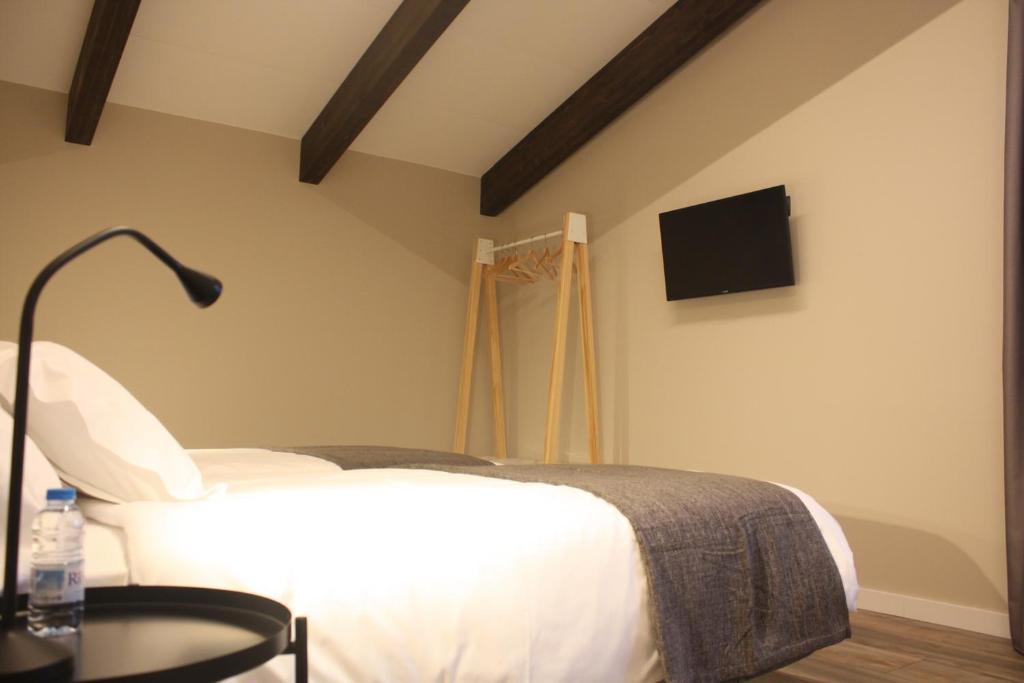 Hotel Els Avets في كامبرودون: غرفة نوم مع سرير وتلفزيون على الحائط