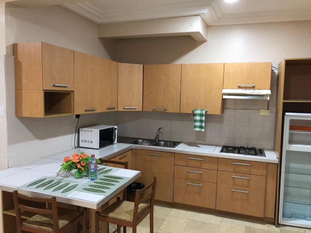 a kitchen with wooden cabinets and a table with flowers on it at Central Hotel - OSU in Accra